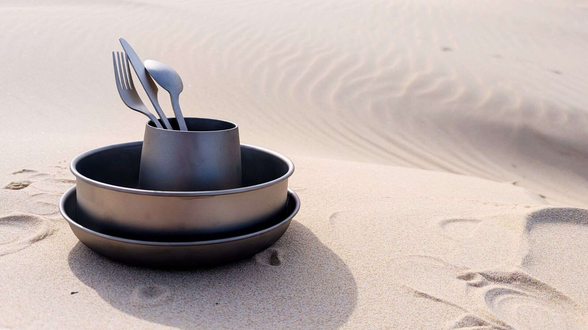 Soulful Camper titanium camping set including lightweight plate, bowl, cup, and cutlery on natural outdoor background