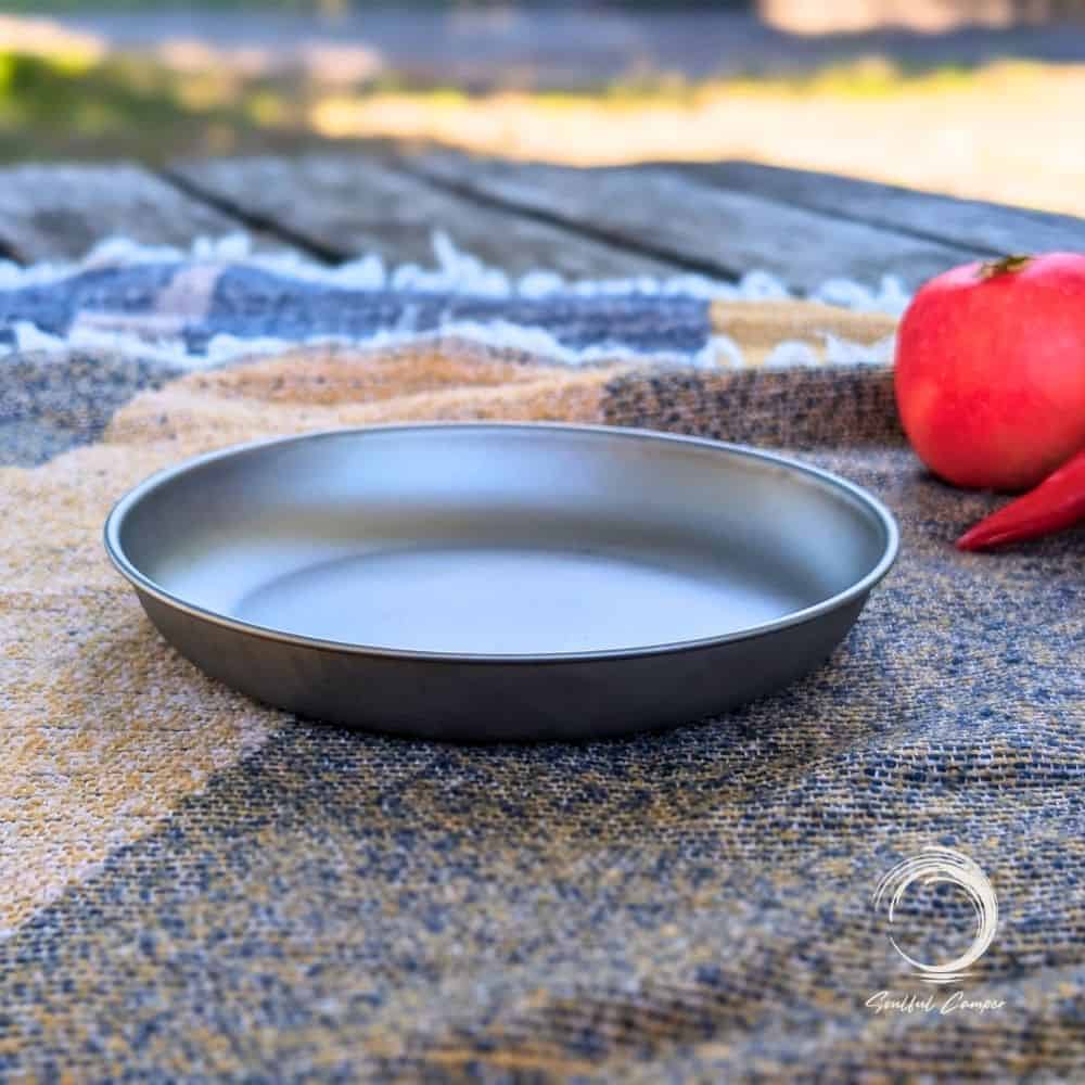 Side profile of titanium camping plate on woven picnic blanket
