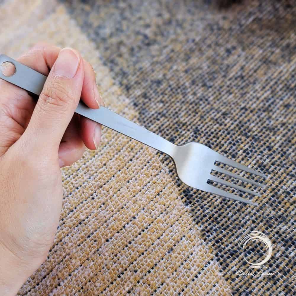 Titanium fork held in hand with rustic woven background