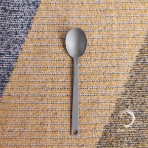 Durable Soulful Camper titanium spoon laid flat on woven camping mat.