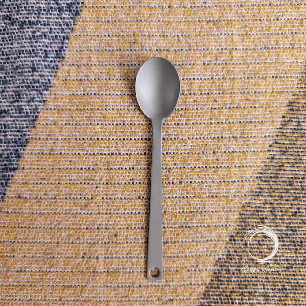 Durable Soulful Camper titanium spoon laid flat on woven camping mat.