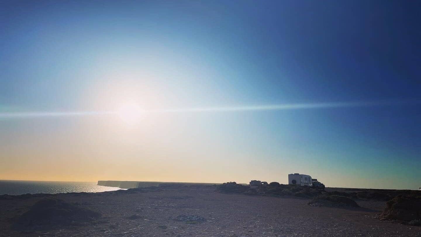 Caravan camping near the dramatic Bunda Cliffs in South Australia at sunset, overlooking the ocean.